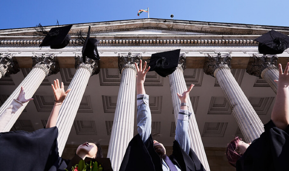 ӰԺ Graduates through caps into the air. 