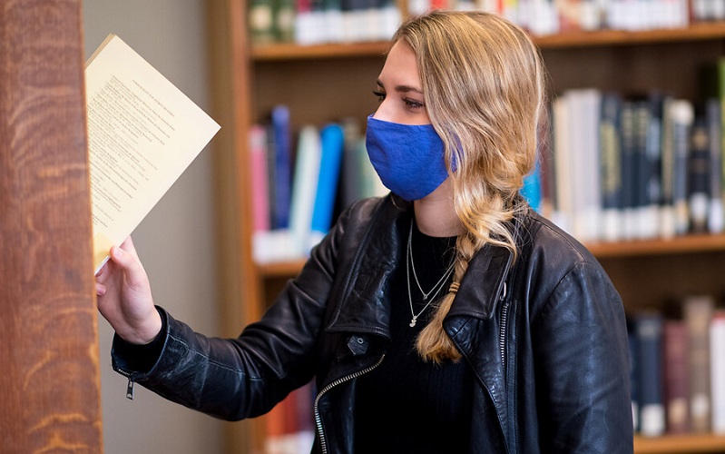 student taking book off library shelf