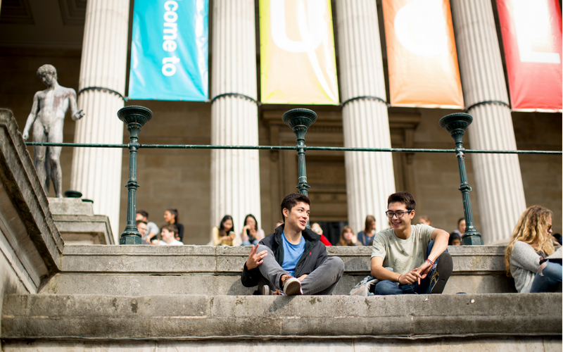 Two students sat on the Portico steps with welcome banners